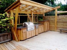 an outdoor bbq and grill area on a deck in the backyard with wooden boards