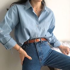 a woman in blue shirt and jeans posing for the camera with her hand on her hip