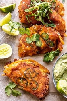 fried chicken with guacamole sauce and lime wedges on a white surface