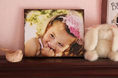 a stuffed animal sitting on top of a wooden shelf next to a framed photo and a teddy bear