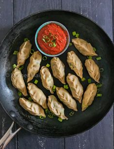 steamed chicken momos in a frying pan with dipping sauce on the side and text overlay