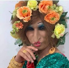 a woman with flowers in her hair and makeup is posing for the camera while wearing an elaborate headdress