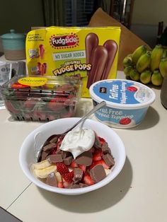 a bowl of fruit and yogurt sitting on a counter next to other food