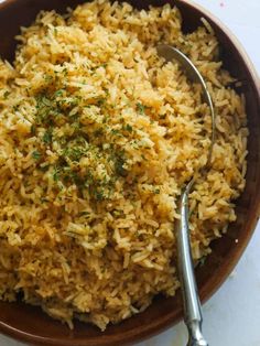 a brown bowl filled with rice and garnished with parsley on the side