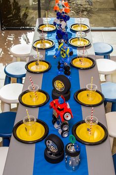 a long table set up with yellow and blue plates, cups, and candy canes