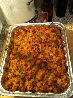 a casserole dish sitting on top of a counter next to a beer bottle