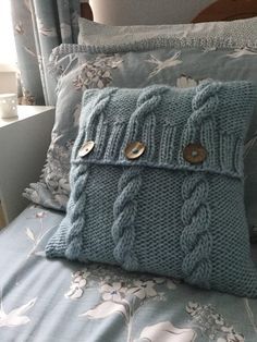 a blue knitted pillow sitting on top of a bed