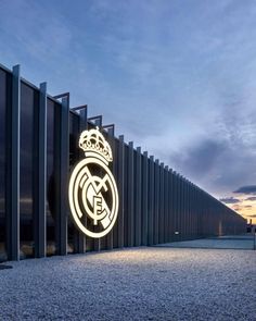 an illuminated sign on the side of a building that has a soccer ball in front of it