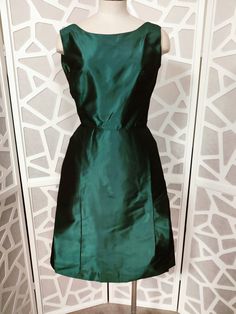 This is a gorgeous unlabelled as to its maker teal green tafetta cocktail dress from the late 50s or early 60s. The dress is sleeveless with a fitted bodice and scooped neckline, is waisted then to a flared skirt section with an extra panel of fabric at the front and wide box pleated at the back. The below knee length skirt section is pelham lined which gives the skirt structure . The back of the dress has a deep V to the  waist and has a large bow centre back giving the dress a bit of a dramati 1950s Style Green Evening Dress, Green 1950s Style Evening Dress, 1950s Style Green Formal Dress, Green 1950s Style Formal Dress, Green Formal Dress In 1950s Style, Early 60s, Scooped Neckline, Large Bow, Flared Skirt