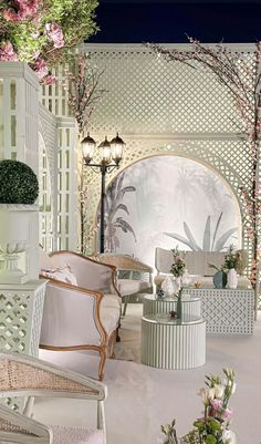 a room filled with lots of white furniture and flowers on the wall next to it