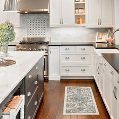 a kitchen with white cabinets and black counter tops, an area rug on the floor