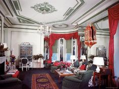 a living room filled with lots of furniture and red drapes hanging from the ceiling