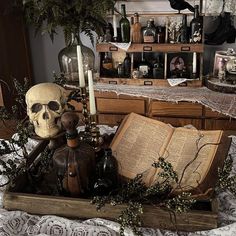 there is a skull sitting on the table next to an open book and some candles