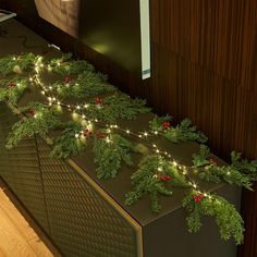 a christmas garland with lights on it is hanging from the side of a wooden wall