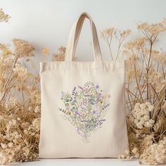 a tote bag sitting in front of some dried flowers