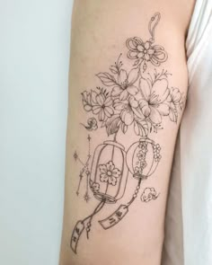 a woman's arm with flowers and a birdcage tattoo