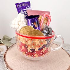 a cup filled with candy and candies on top of a wooden table next to other items