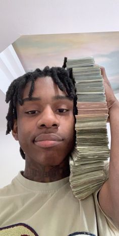 a man holding up stacks of money in front of his face and looking at the camera