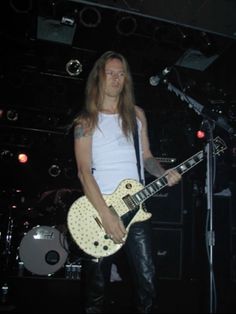 a man with long hair playing an electric guitar