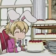 a person sitting at a table with a cake in front of them and an anime character behind it