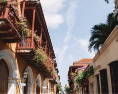 an alley way with flowers growing on the balconies