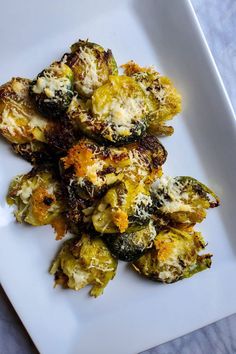 a white plate topped with brussel sprouts covered in cheese