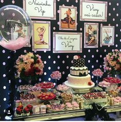 a table topped with lots of cakes and desserts next to pictures on the wall