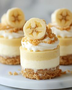 three small desserts with bananas and whipped cream on top are sitting on a white plate