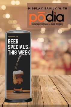 a beer can sitting on top of a wooden table next to a sign that says popdia