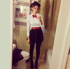 a woman in a white shirt and red bow tie taking a selfie with her cell phone