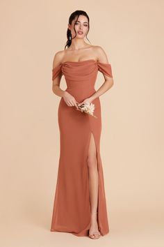 a woman in an off the shoulder dress posing with her hands on her hips and holding flowers