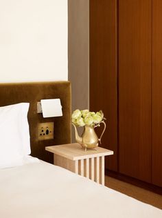 a hotel room with a bed, nightstand and flowers in a vase on the end table