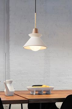 a wooden table with two white vases on it and a light hanging over it