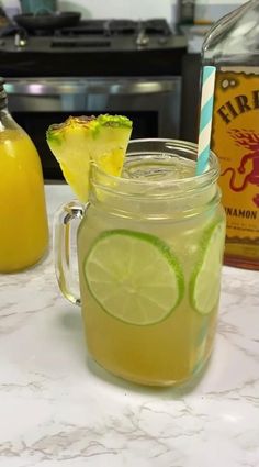 a pitcher of lemonade next to a glass with a slice of lime