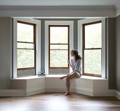 a woman sitting on a window sill looking out the window