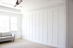 a living room with white paneling and a couch in front of a large window