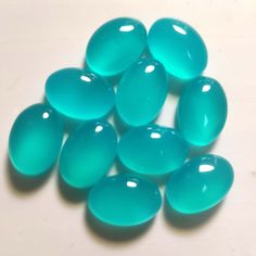 some very pretty blue colored stones on a white surface with water droplets in the middle