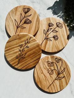 four wooden coasters with flowers etched on them