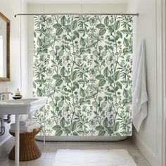 a bathroom with a shower curtain that has green leaves on it, and a white sink