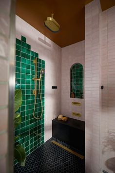 a bathroom with green tile and gold trim on the shower head, mirror, and sink