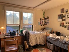 a dorm room with two beds, desks and pictures on the wall above them