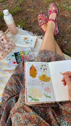 a woman is sitting on the grass reading a book