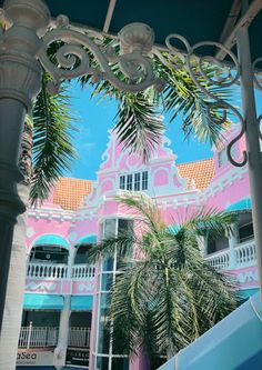 a pink building with palm trees in the foreground and stairs leading up to it