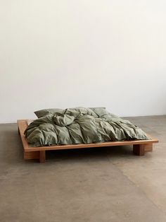 an unmade bed sitting on top of a wooden platform next to a white wall