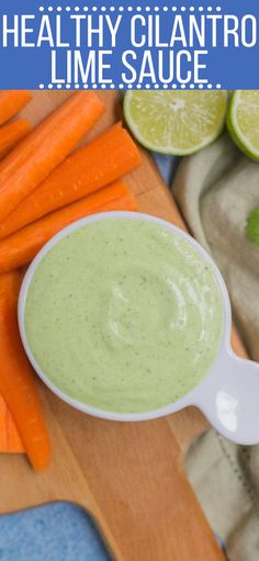 a bowl of dip surrounded by sliced carrots and lime