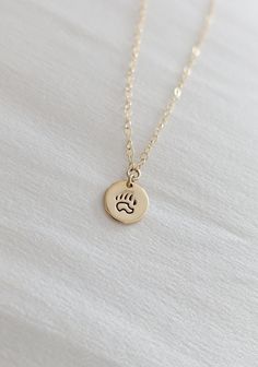 A dainty bear paw necklace with a big message! Wear this piece of jewelry as a reminder that you can conquer anything big or small. Perfect for any adventurer, weekend nomad, or blissful free spirit. Great to gift or to treat yourself! --------------------------- I T E M ∙ D E T A I L S * Option of sterling silver or 14k gold-filled necklace - Great for those sensitive to specific metals * Hand-stamped design on a 9mm charm * Photo features 16-inch necklace * Packaged neatly + securely in a reus Paw Necklace, Forest Jewelry, Necklace Packaging, 16 Inch Necklace, Bear Paw, Black Sharpie, Bear Paws, Hand Stamped Jewelry, Funky Jewelry