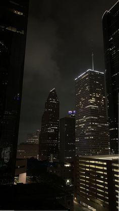 the city skyline is lit up at night, with skyscrapers in the foreground