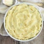 a white bowl filled with mashed potatoes on top of a wooden table