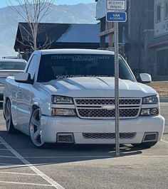 a white truck parked in a parking lot next to a street sign and some buildings