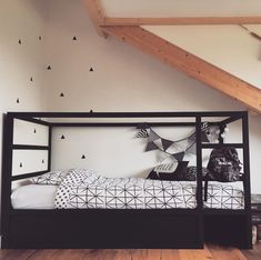 a black and white bed in a room with wooden floors, an attic style ceiling